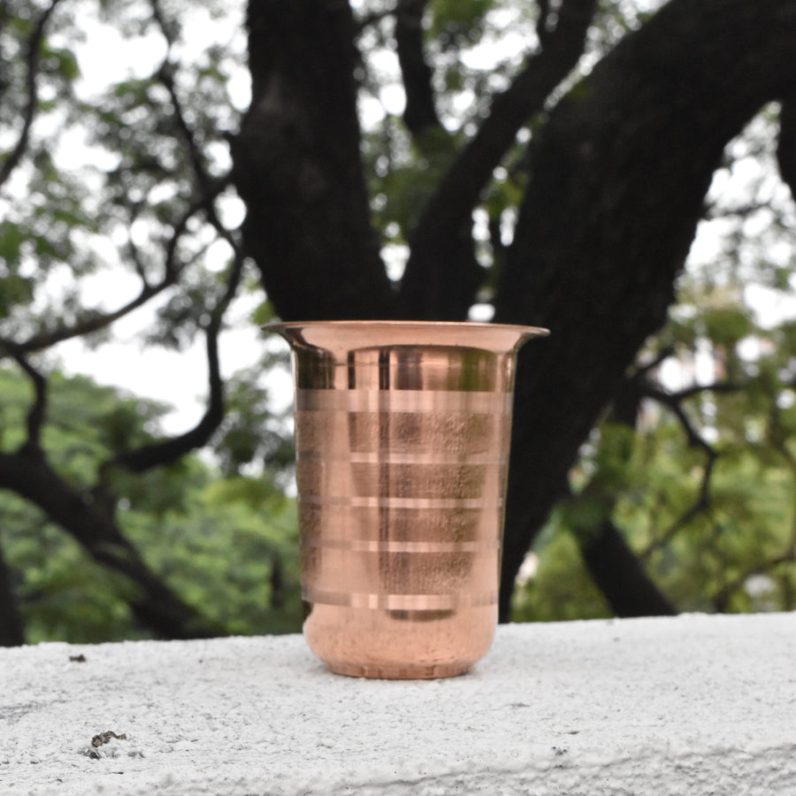 Copper cup on a concrete surface with trees in the background