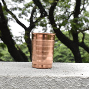 Copper tumbler on a concrete surface with trees in the background